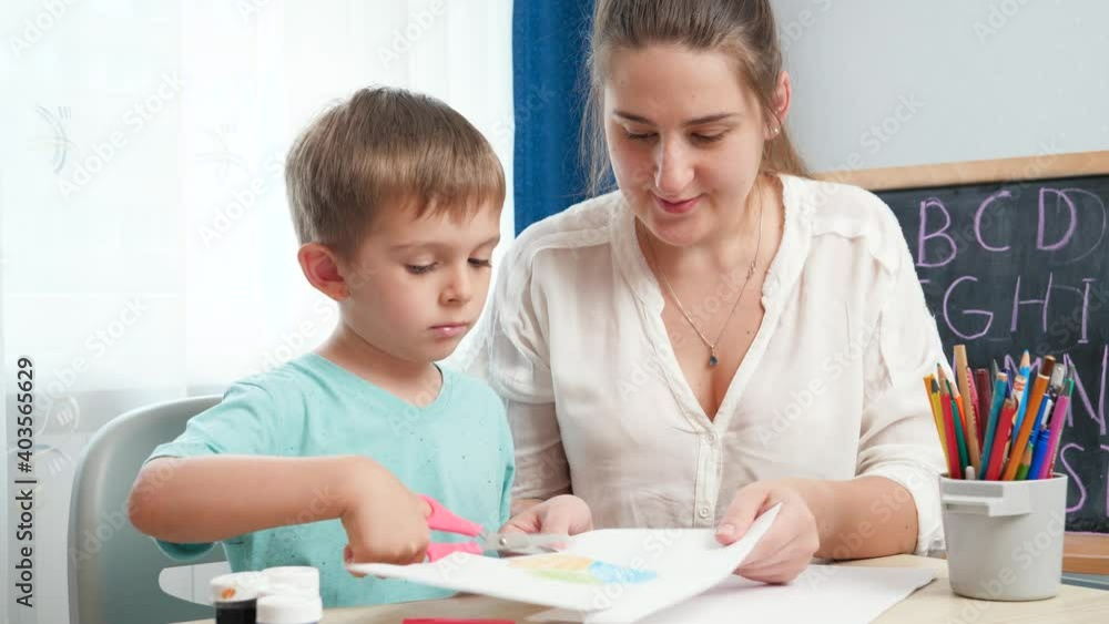 Mother with little son cutting colorful paper while doing homework. Child educating and studying at home during lockdown and self isolation, Mother with little son cutting colorful paper while doing homework. Child educating and studying at home during lockdown and self isolation,