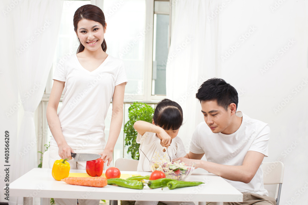 A happy family of three preparing a salad