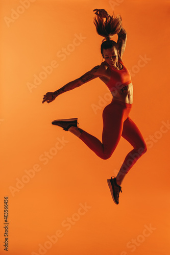 Portrait of fit woman jumping in air during workout