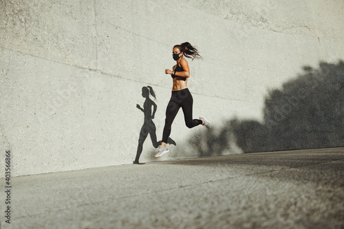 Athletic woman running wearing protective face mask