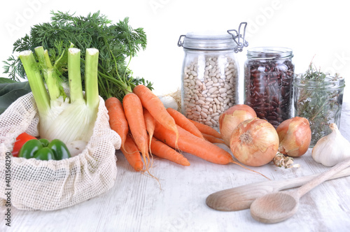 fresh vegetables in a reusable  bag   and dry bean in jar with onions and gar...