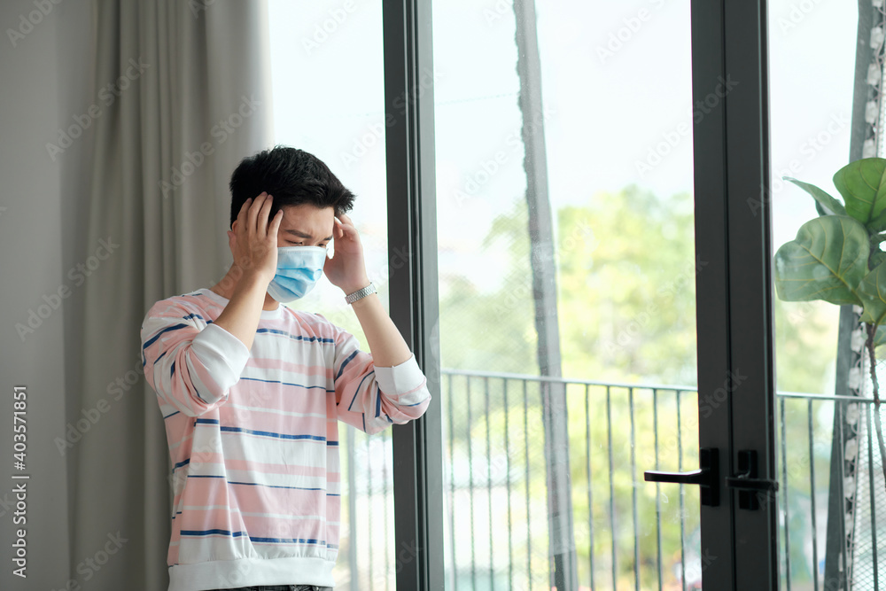COVID-19. Sick man of coronavirus looking through the window and wearing mask protection and recovery from the illness in home. COVID-19. Sick man of coronavirus looking through the window and wearing mask protection and recovery from the illness in home.