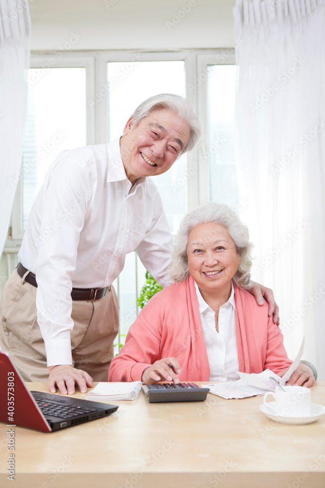 An old couple using laptop and calculator An old couple using laptop and calculator