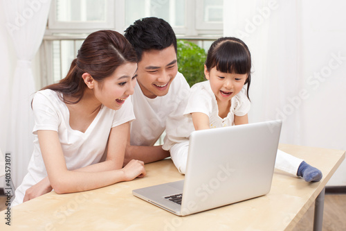 Little girl using laptop with her parents