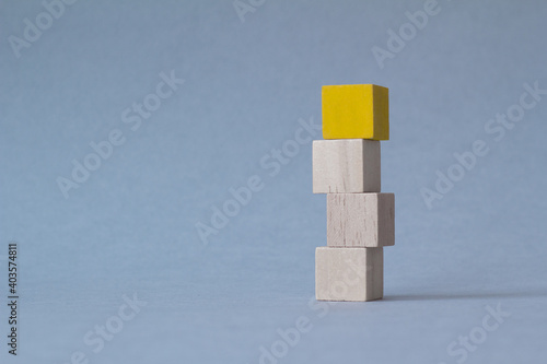 Top view of wooden blocks on blue, one yellow cube. leadership concept