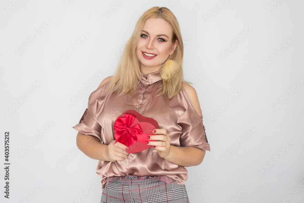 dreaming woman in pink blouse holding red gift box heart