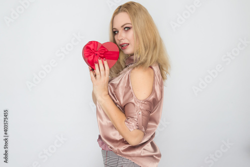 Fototapeta Naklejka Na Ścianę i Meble -  dreaming woman in pink blouse holding red gift box heart