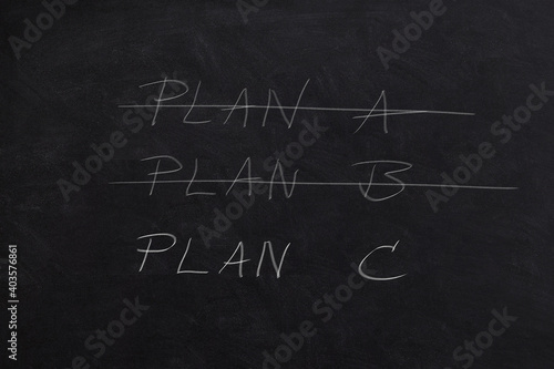 Crossing out Plan A and Plan B and writing Plan C on a blackboard