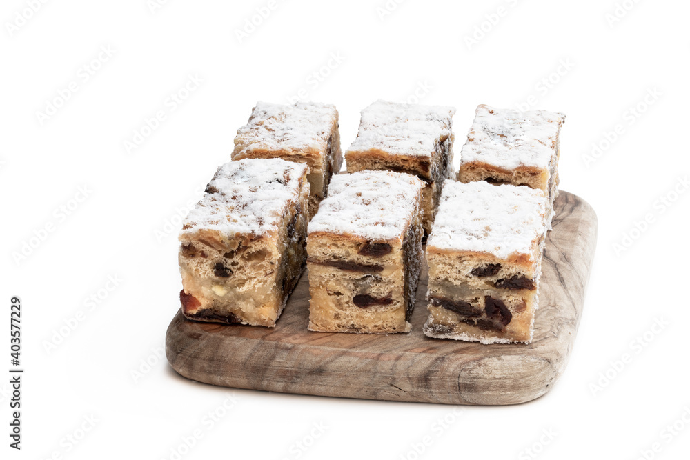 Christmas stollen slices with icing sugar on wooden board isolated on white Christmas stollen slices with icing sugar on wooden board isolated on white