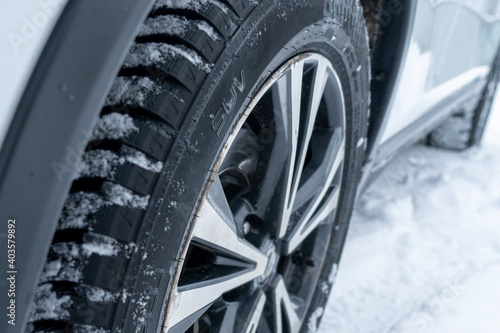winter tires of a white modern crossover close-up on a snow-covered road, selective focus, tinted image