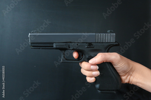 Hands holding gun isolated on dark background.