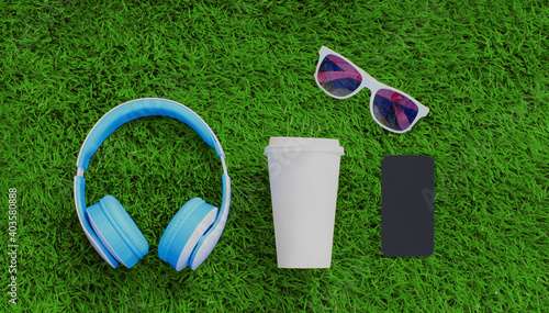 Close up blue wireless headphones, smartphone, coffee cup, sunglasses on a green grass background, top view
