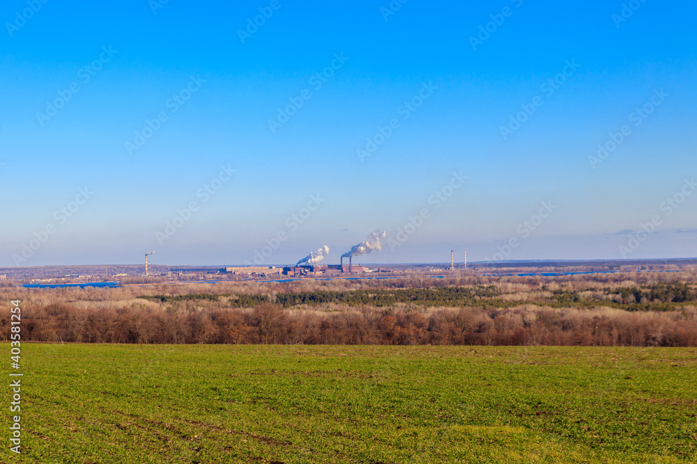 View of green wheat field and smoke pipes of factory at spring View of green wheat field and smoke pipes of factory at spring