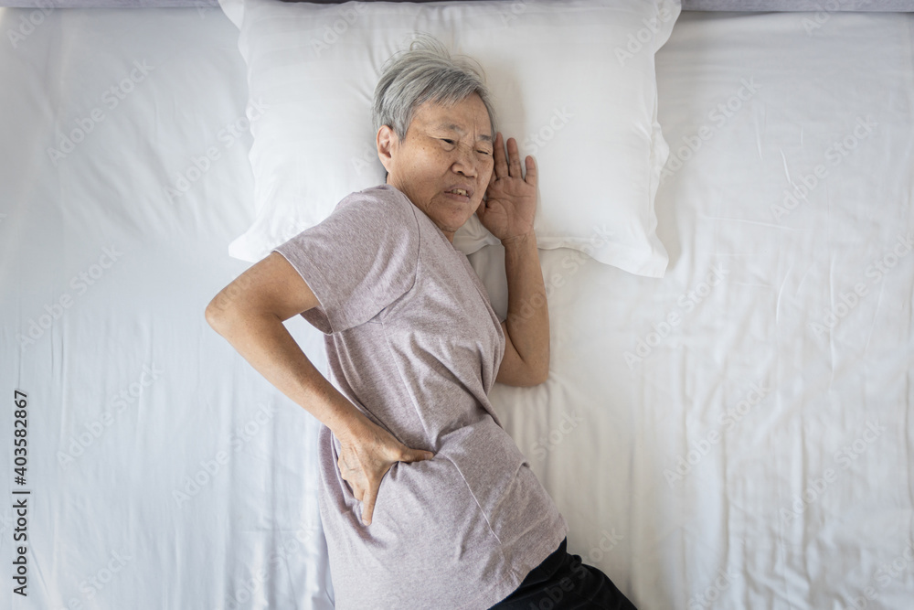 Asian senior woman suffering from backache,sore waist while sleep