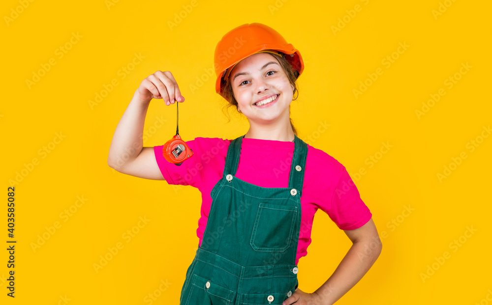 happy child hold tape measure. kid builder wear helmet. teen girl in hard hat and uniform. building and construction. concept of repair. Little girl using a measuring tape. engineer