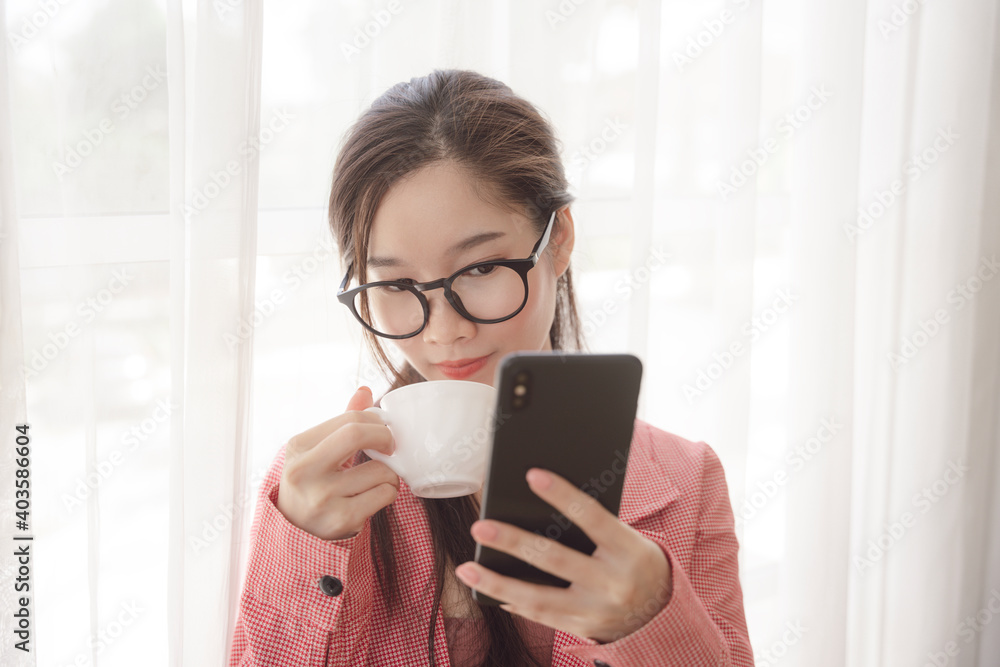 Asian beauty woman wear pink jacket and eyeglasses using smartphone and drinking coffee. Asian beauty woman wear pink jacket and eyeglasses using smartphone and drinking coffee.