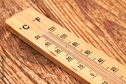 Close-up photo of household alcohol thermometer showing temperature in degrees Celsius on a wooden background. Close-up, selective focus