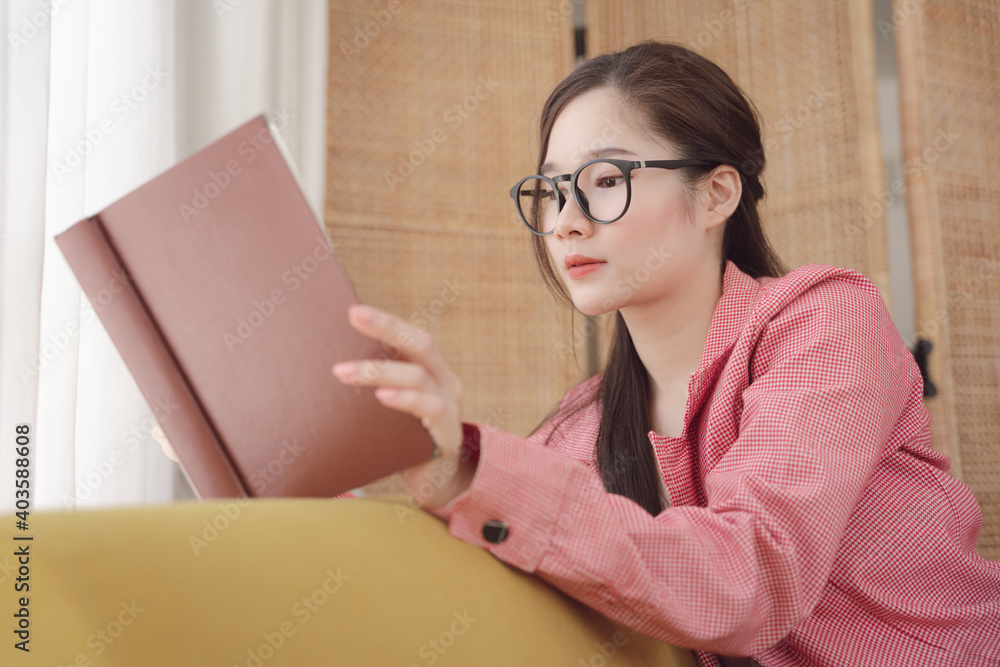 Side view - asian beauty woman wear eyeglasses and pink jacket reading a book at home. Side view - asian beauty woman wear eyeglasses and pink jacket reading a book at home.