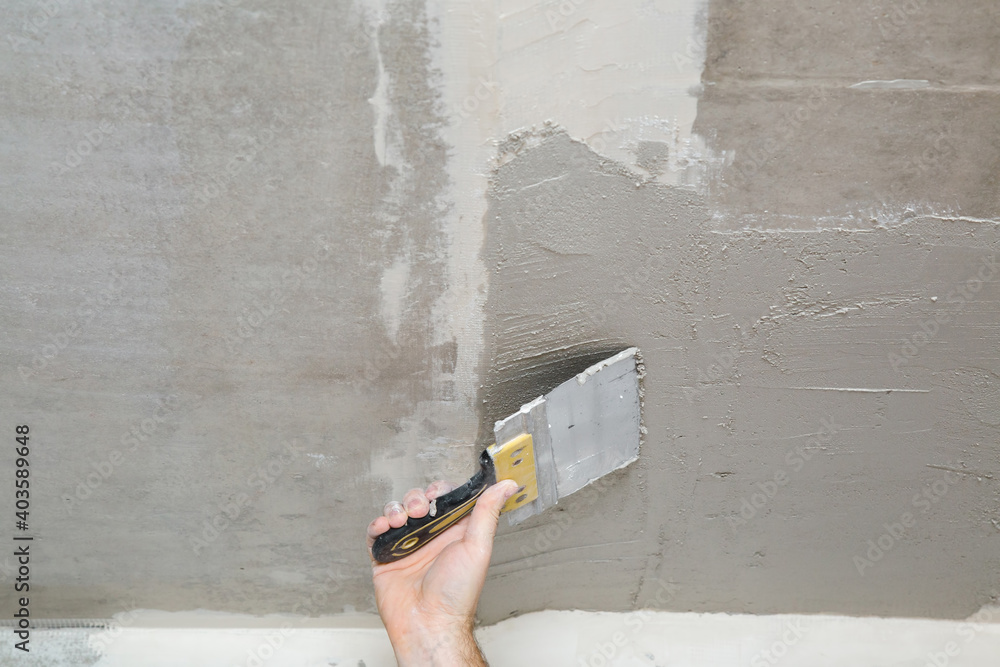 Young adult man hand using spatula and plastering ceiling with putty. Closeup. Repair work of home. Young adult man hand using spatula and plastering ceiling with putty. Closeup. Repair work of home.