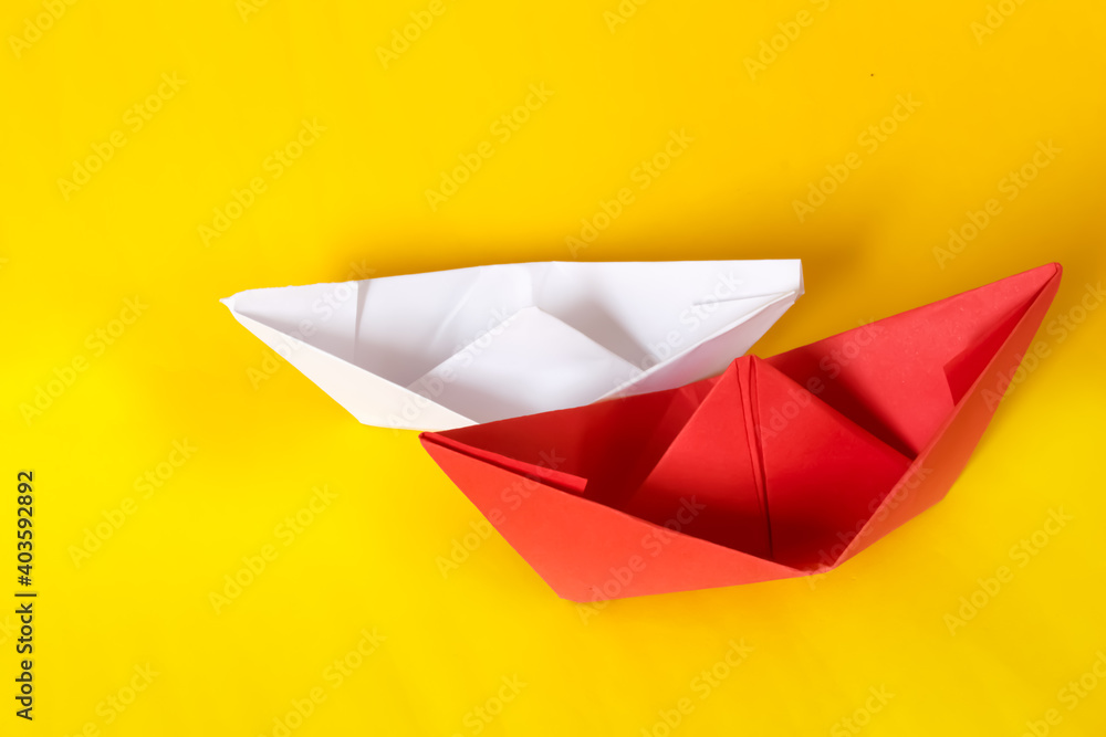 White and red paper ship isolated on yellow background. Origami boats. Concept of tolerance for differences White and red paper ship isolated on yellow background. Origami boats. Concept of tolerance for differences