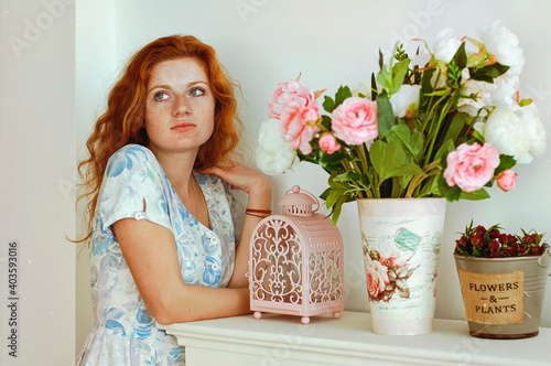 Portrait of young redhead woman with freckles in blue dress in sunny spring day at home. Natural beauty. Woman's Day. Greeting card. 
