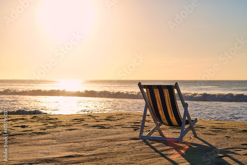 Wooden lounger at sea sunset. Sea dawn and sandy beach and armchair. Calm and tranquility. High quality photo