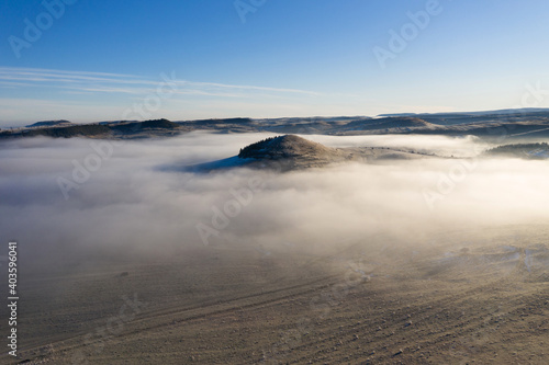 Flying over hills in mystic foggy winter morning. Aerial view