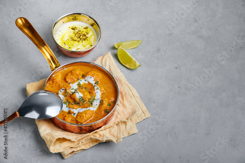 Murgh Makhani or Butter Chicken in copper bowl on gray concrete table top. Indian Cuisine dish with chicken meat and creamy masala. Asian food and meal. Copy space photo