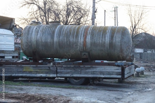 one big dirty gray iron barrel cistern on a truck trailer on the street