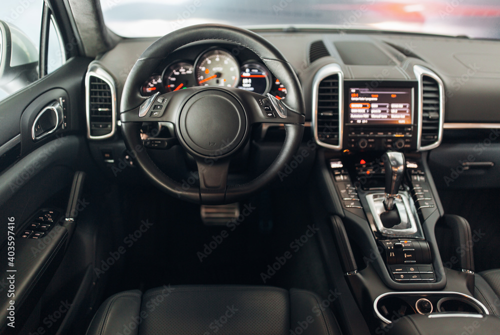 Expensive suv car interior with the steering wheel, multimedia dashboard, and gearbox handle