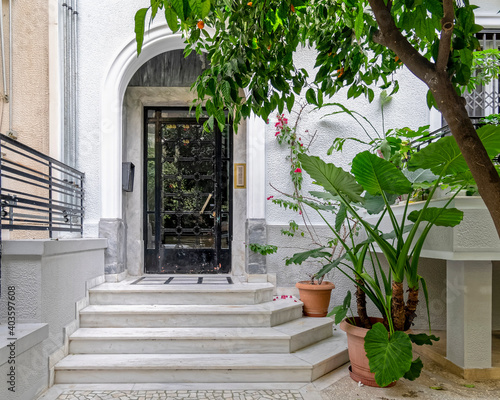 Fototapeta Naklejka Na Ścianę i Meble -  classic design residential building main entrance with marble stairs, arched door and potted plants