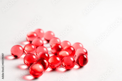 Three Red Pills Capsules with Many in Background Isolated on a White