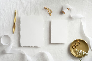 Beautiful wedding invitation cards template with golden decorations on white textile background top view. Romantic flat lay composition.