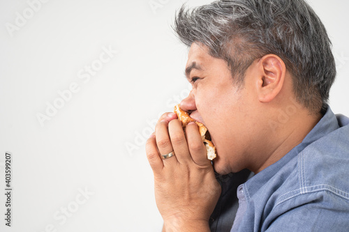 Asian Middle aged man holds and eating a hamburger deliciously Concept of binge eating disorder (BED) and Relaxing with Eating junk food and unhealthy foods.
