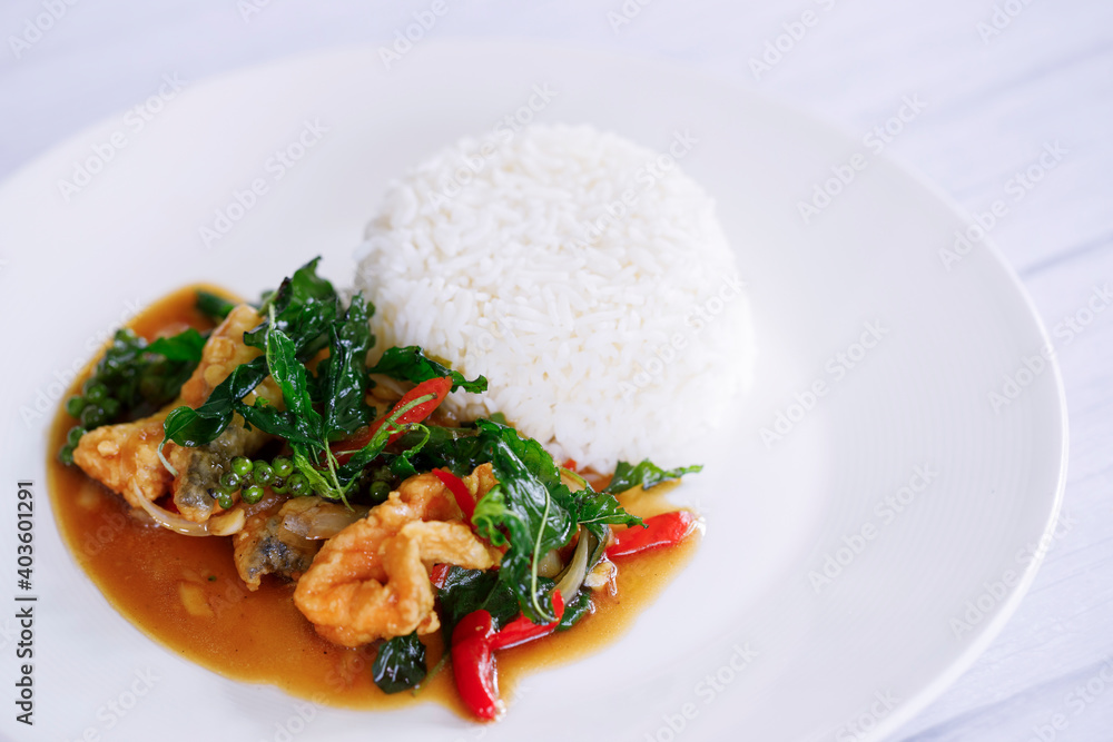 Spicy Stir fry Thai spicy holy basil with Fried Fish served on plain rice Spicy Stir fry Thai spicy holy basil with Fried Fish served on plain rice