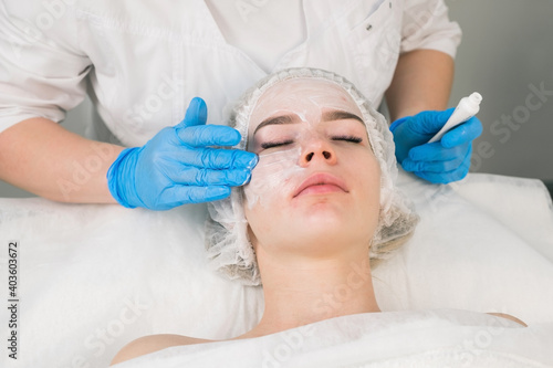 Treatment, cure of face skin in cosmetology clinic. Beauty procedure with problem skin for young woman. Cosmetologist doctor is applying cream with anesthesia before PRP therapy procedure.