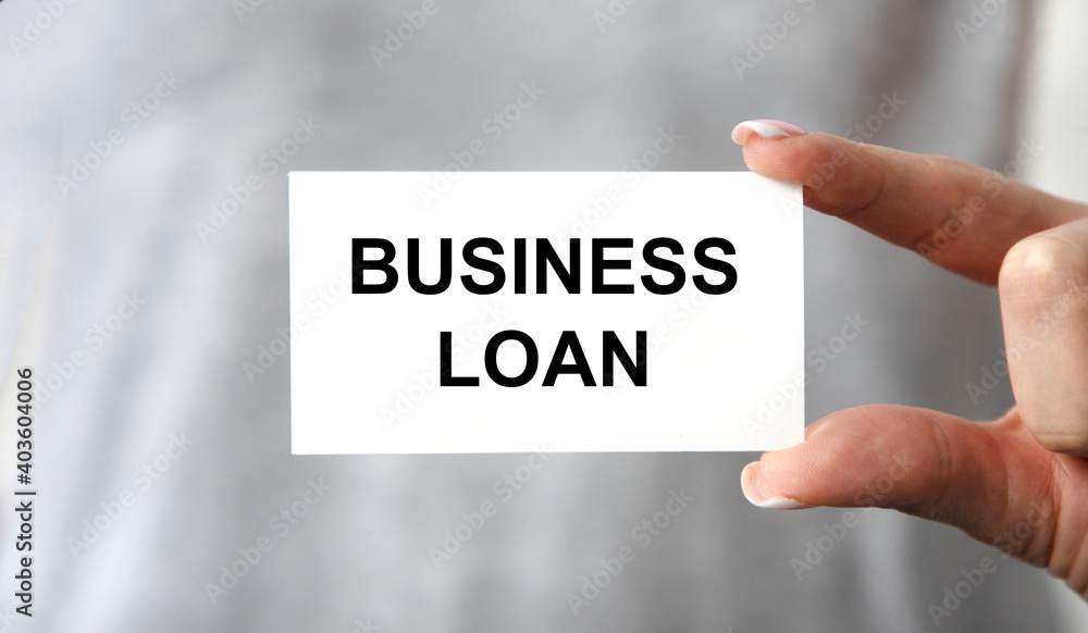 The girl holds a business card with the text Business Loan. The girl holds a business card with the text Business Loan.