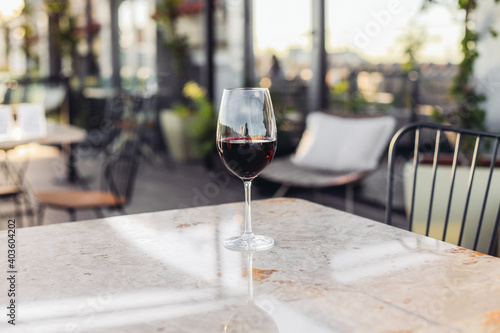 A glass of red wine on a marble table in a fancy restaurant, daylight 