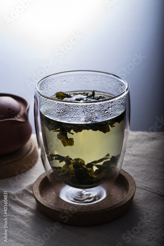 A green tea in a double glass cup on a linen cloth against white background