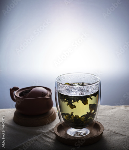 A green tea in a double glass cup on a linen cloth against white background