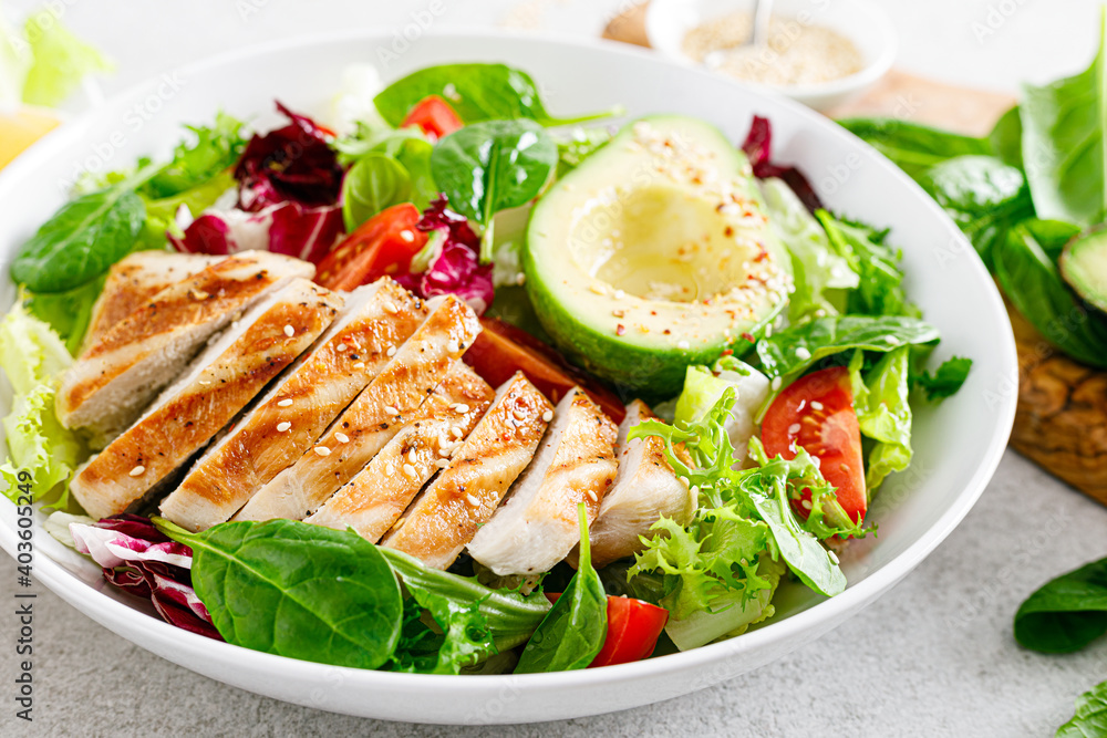 Grilled chicken meat and fresh vegetable salad of tomato, avocado, lettuce and spinach. Healthy and detox food concept. Ketogenic diet. Buddha bowl dish on white background Grilled chicken meat and fresh vegetable salad of tomato, avocado, lettuce and spinach. Healthy and detox food concept. Ketogenic diet. Buddha bowl dish on white background