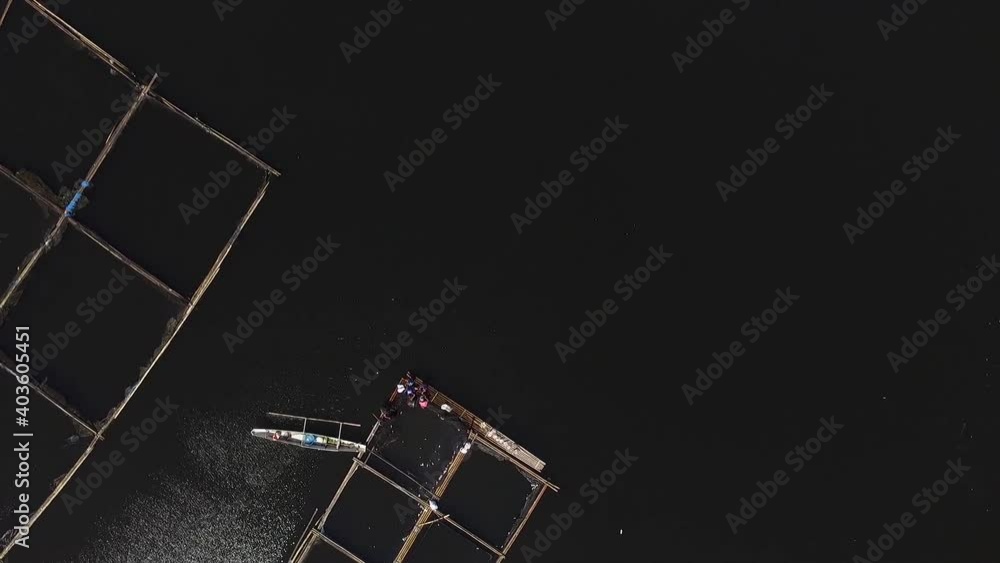 San Pablo City, Laguna, Philippines - January 7, 2021: Local fishermen working in floating fish cages on Sampaloc Lake. Drone aerial shot San Pablo City, Laguna, Philippines - January 7, 2021: Local fishermen working in floating fish cages on Sampaloc Lake. Drone aerial shot