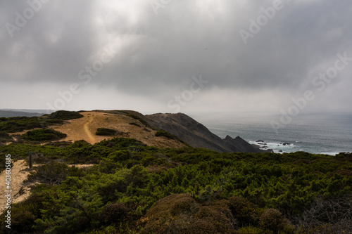 Beautiful scene on the Amoreira beach trail, part of the the Vicentina Route, mixing sandy beaches, cliffs and vegetation all in once. With a dramatic sky. Aljezur, Portugal. © JoaLacerda