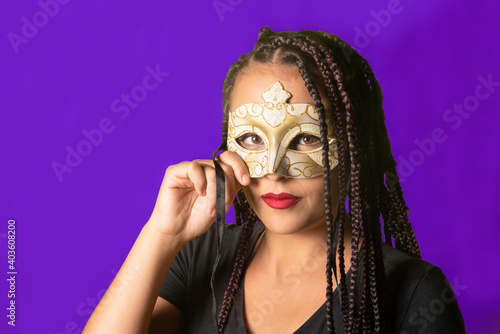 Beautiful girl with braids in her hair and carnival mask, colorful background, selective focus.