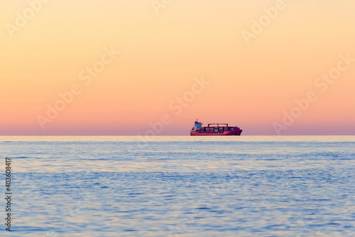Container Cargo ship on the horizon at sunset.