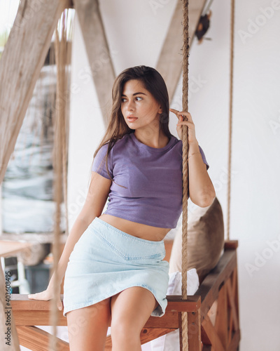 A beautiful girl sits on a swing in a cafe.