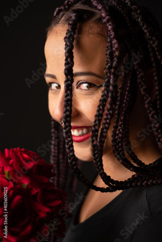 Happy girl, beautiful girl with a bouquet of red roses in her hand, black background, selective focus.