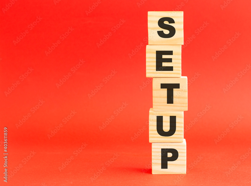 Wooden cubes with word SETUP. Wooden cubes on a red background. Free space on the left. Wooden cubes with word SETUP. Wooden cubes on a red background. Free space on the left.