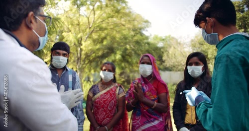 Slow-motion of health care workers giving instructions to patients, male female young aged with face mask of different religions - Hindu Muslim Islam Sikh, outdoors day time summer sun India