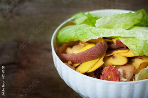 Container of domestic organic food waste ready to be composting on stylish wooden background. Lets compost your waste!
